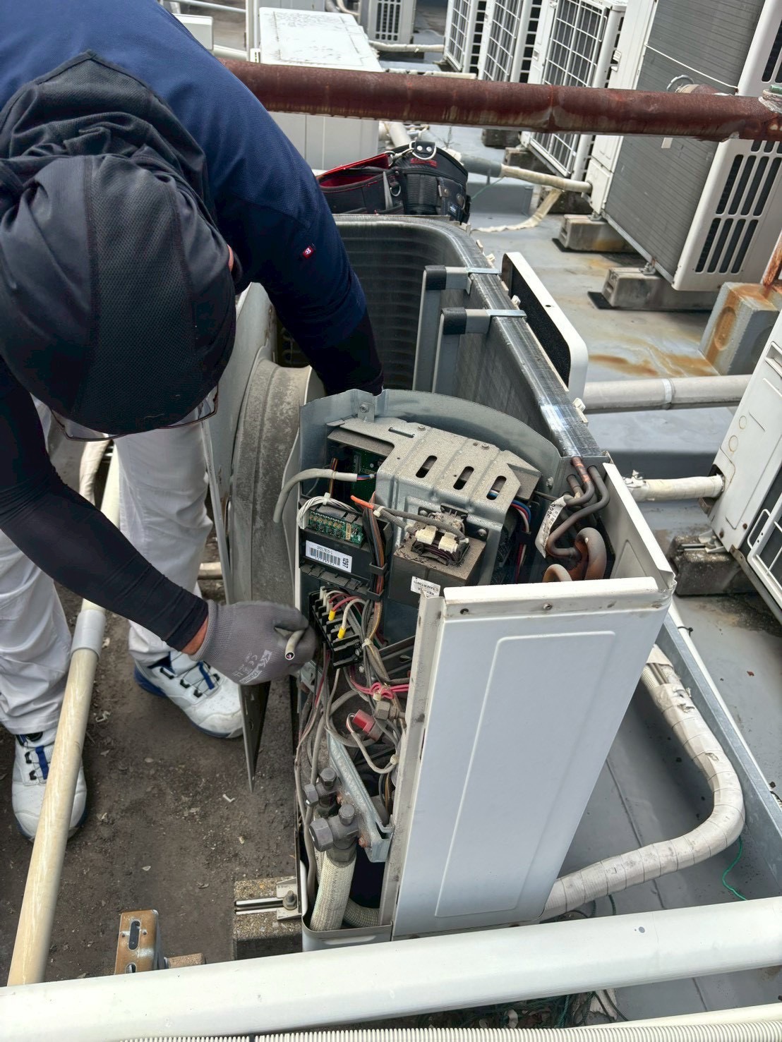 室外機の内部を確認する日綜メンテナンスの作業スタッフ